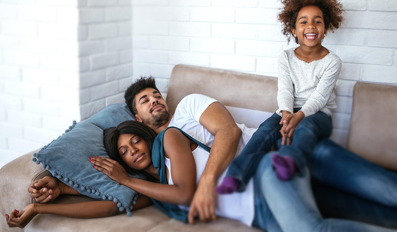 adults-and-kids-naptime A family getting ready for a nap sitting on their couch.